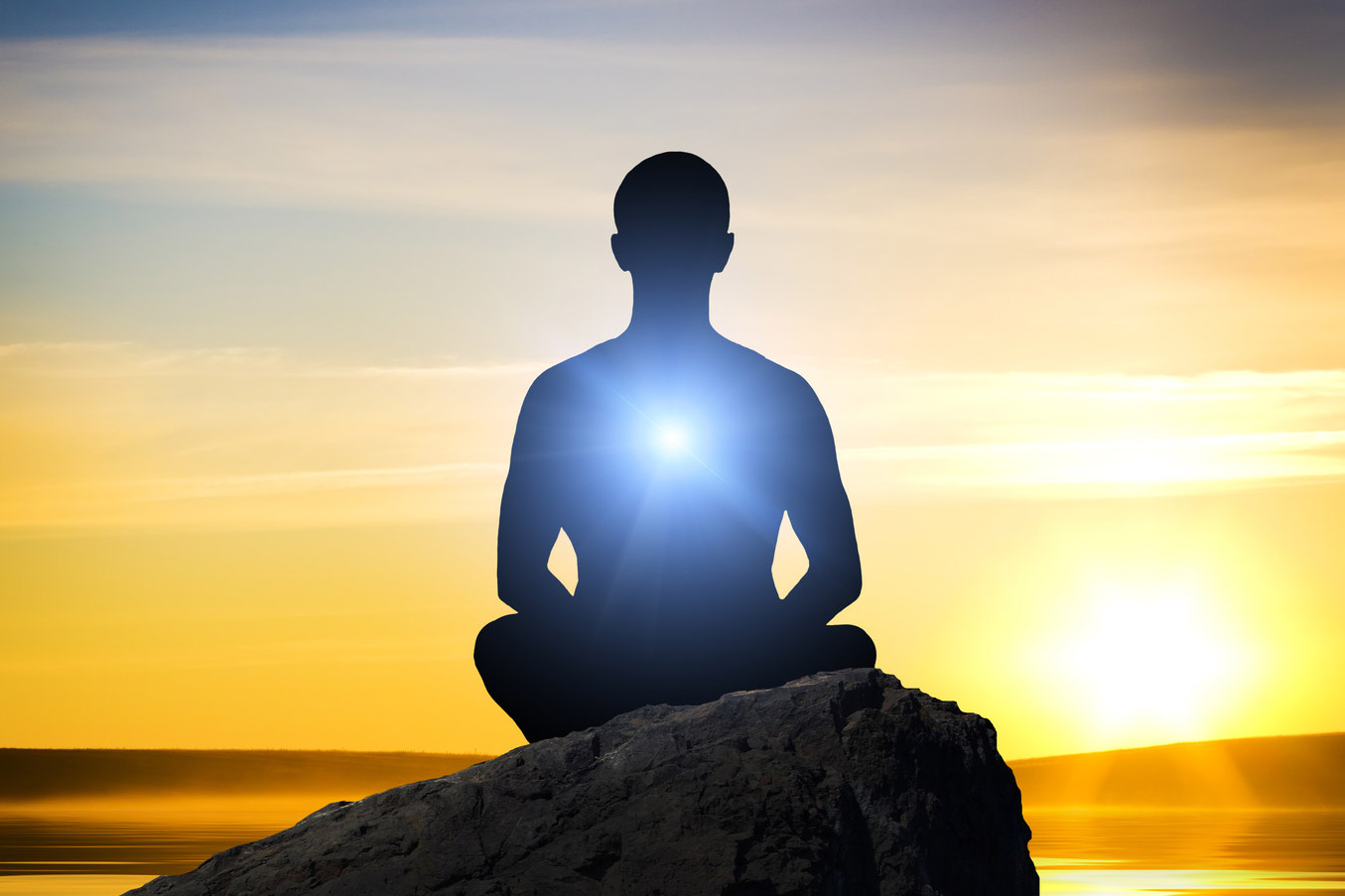 A person sits on a rock at sunrise, a bright light emanates from the center of their chest representing personal resiliency